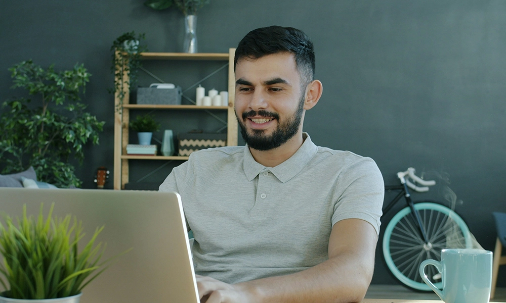 wAPhLocO Man sitting at his desk using his computer - he looks happy and satisfied.